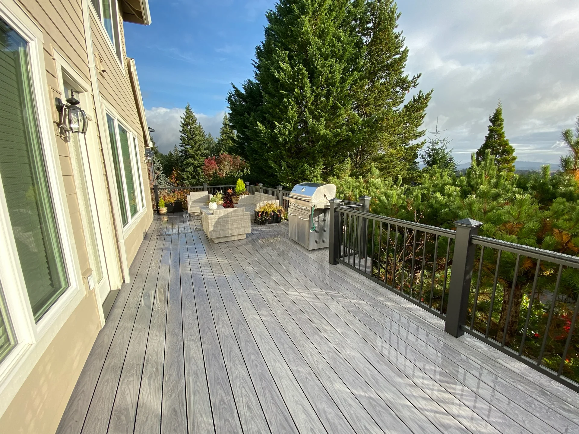 Finished composite deck with black aluminum railing beside a Portland-area home